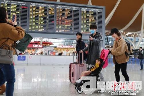 旅客带着孩子前往办票柜台办理登机手续。　殷立勤 摄