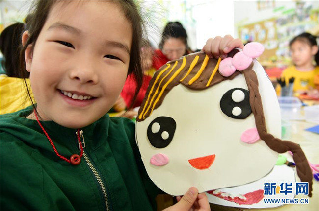 5月7日,在江苏省镇江市解放路幼儿园,一名小朋友展示自制的笑脸卡